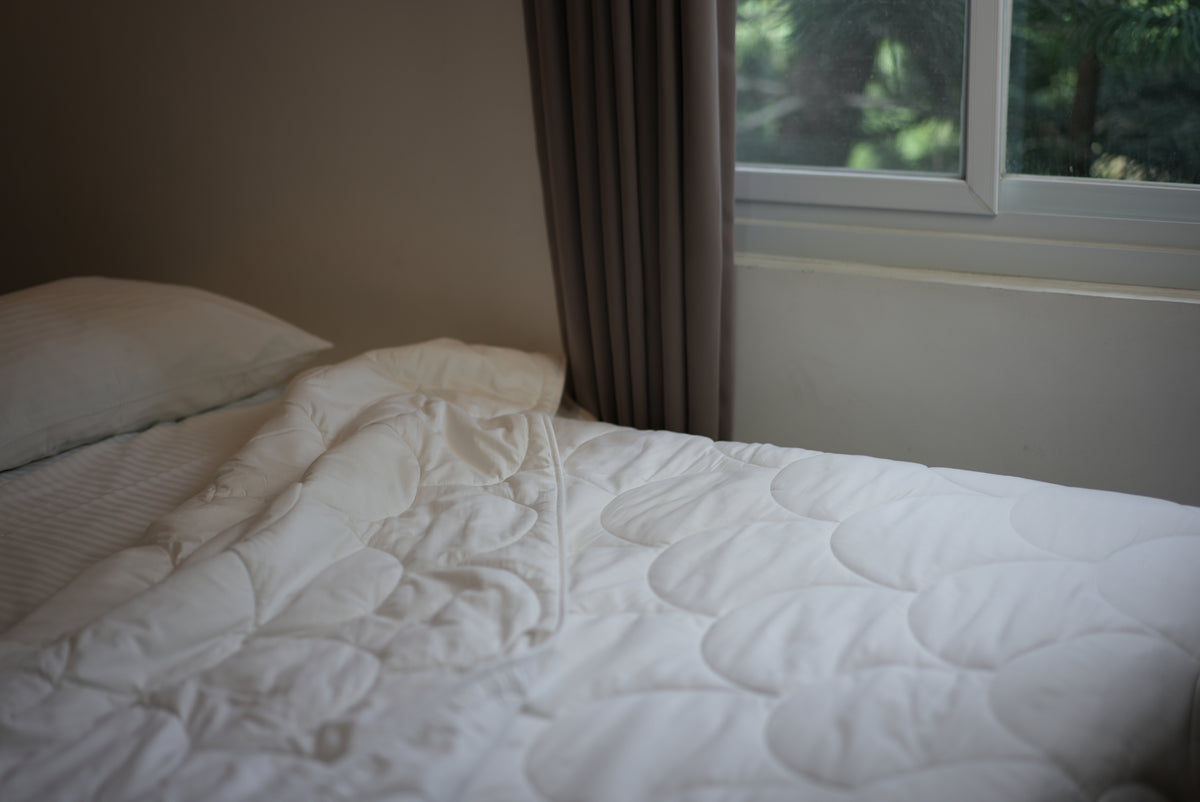A Larke duvet on a bed beside a bright window