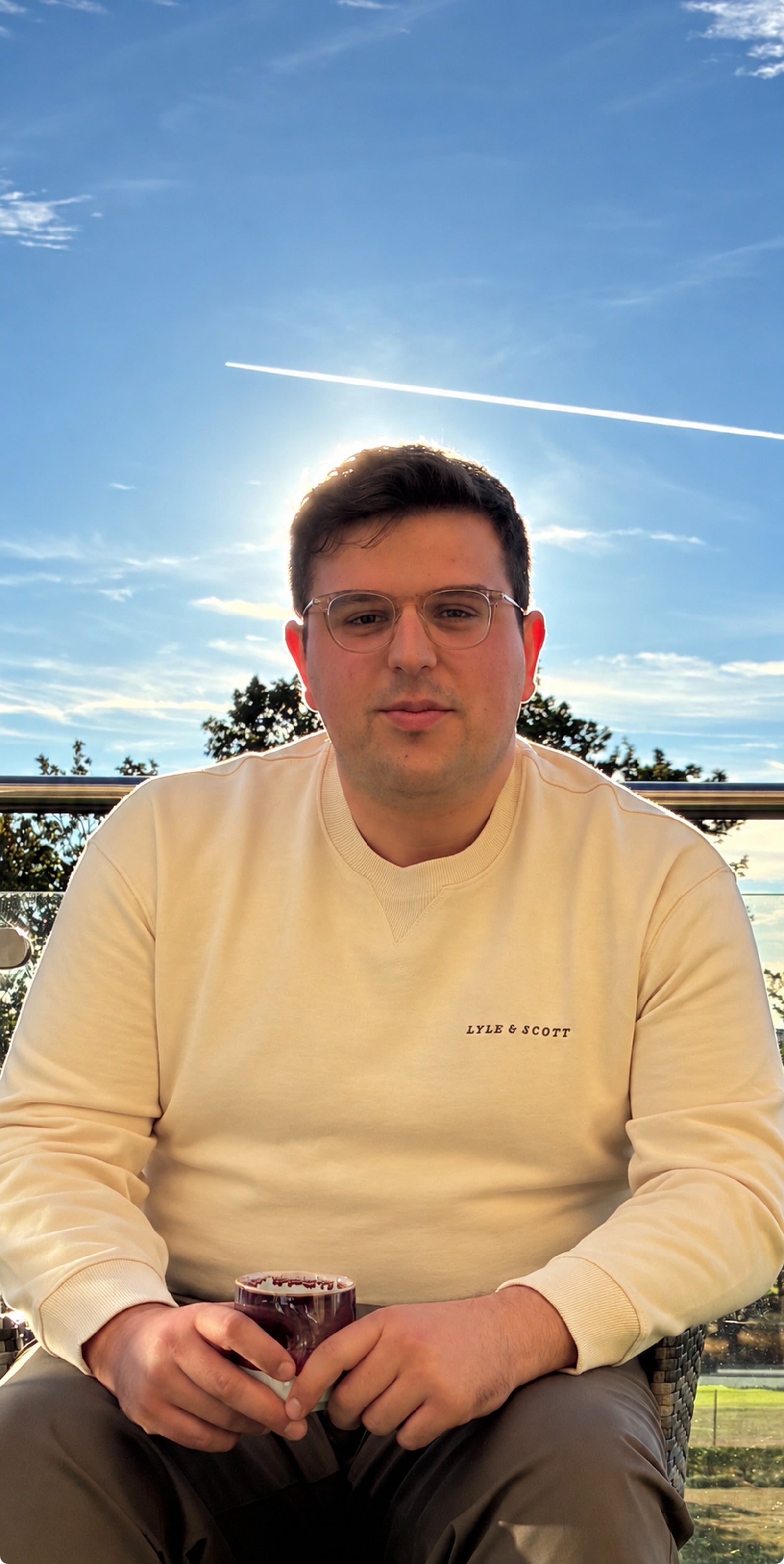 Larke founder Reuven Sherman sitting on a bed in cream loungewear